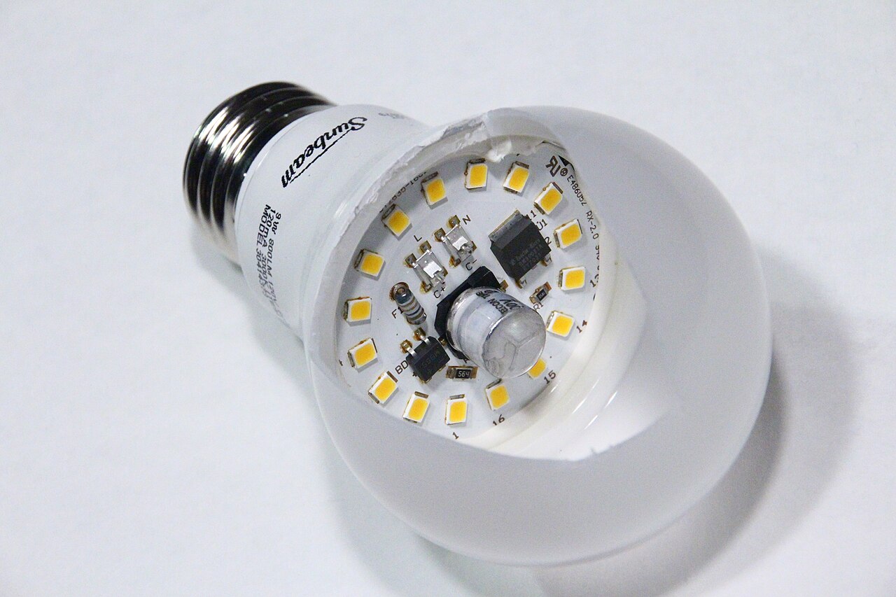 Vue d’une lampe LED E27 dont le circuit interne du driver est visible entre le culot et les LED
